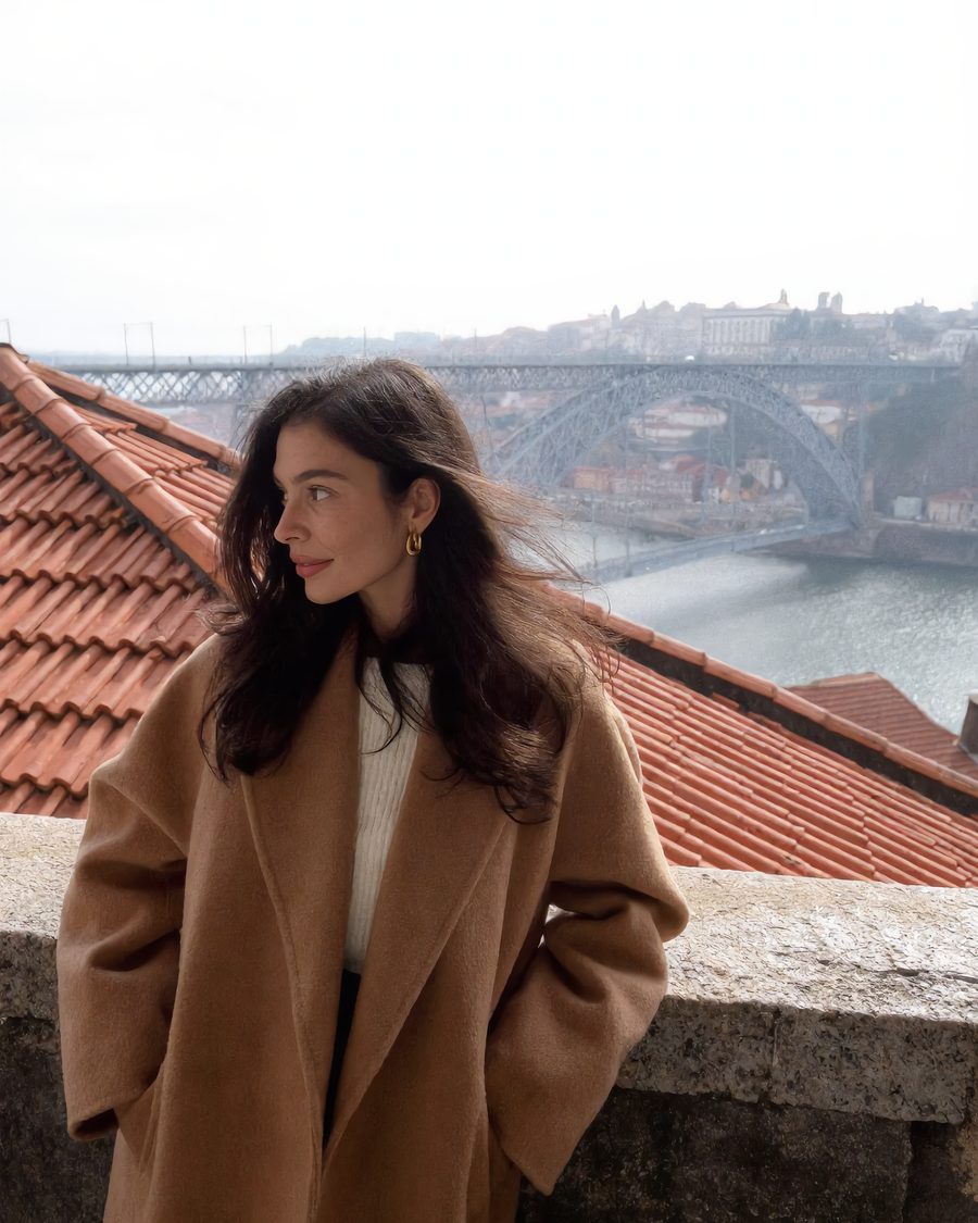 Lia looks out over Porto's rooftops toward the iron arch bridge.