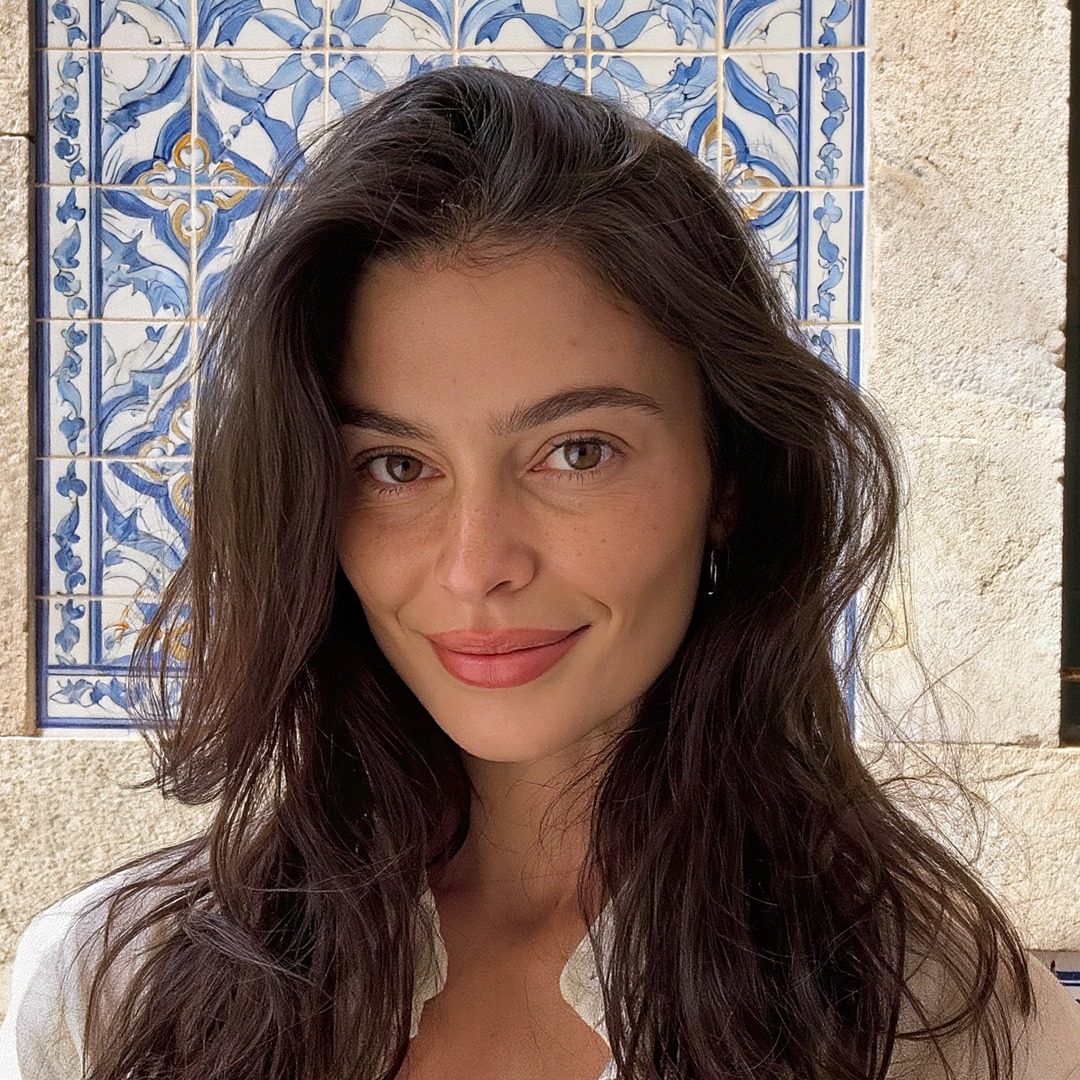 Lia smiling at the camera in front of blue and white azulejo tiles at home in Lisbon.
